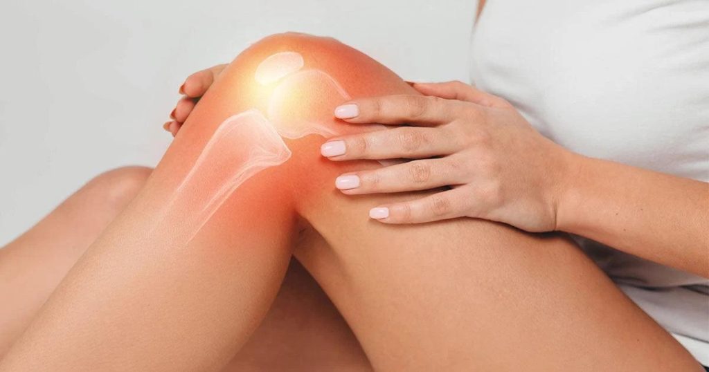Person holding a painful knee while seated