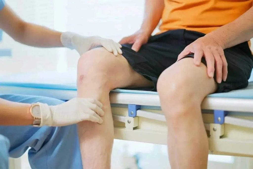 Clinician examining a patient’s knee during an evaluation