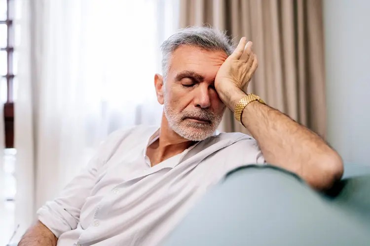 Older adult seated at home while feeling low energy