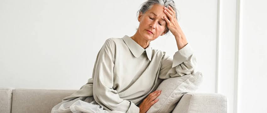 Older adult seated with a hand on the forehead due to fatigue