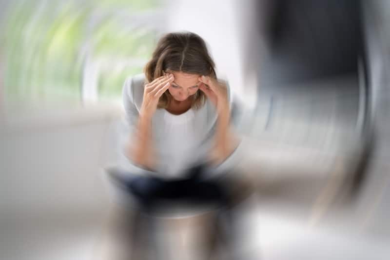 Person seated while experiencing dizziness and blurred surroundings