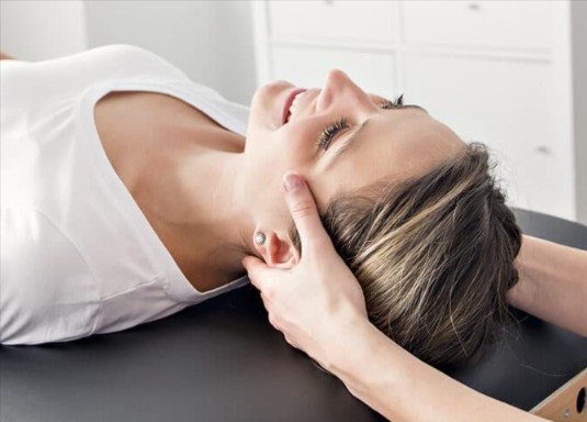 Clinician positioning a patient’s head during a vertigo assessment